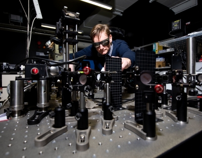 A researcher wearing glasses operating with machinery in a lab