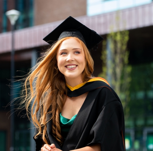 Girl on graduation day smiling in front of Glucksman Library