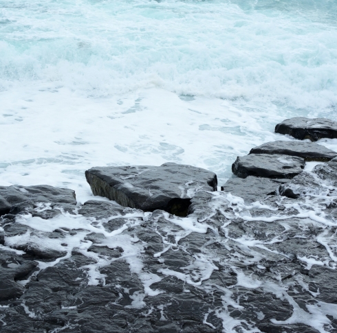 A picture of rocks by the seaside, with water running over them.