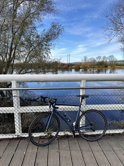 Photo of a blue bike leaning against a bridge with the River Shannon in the background