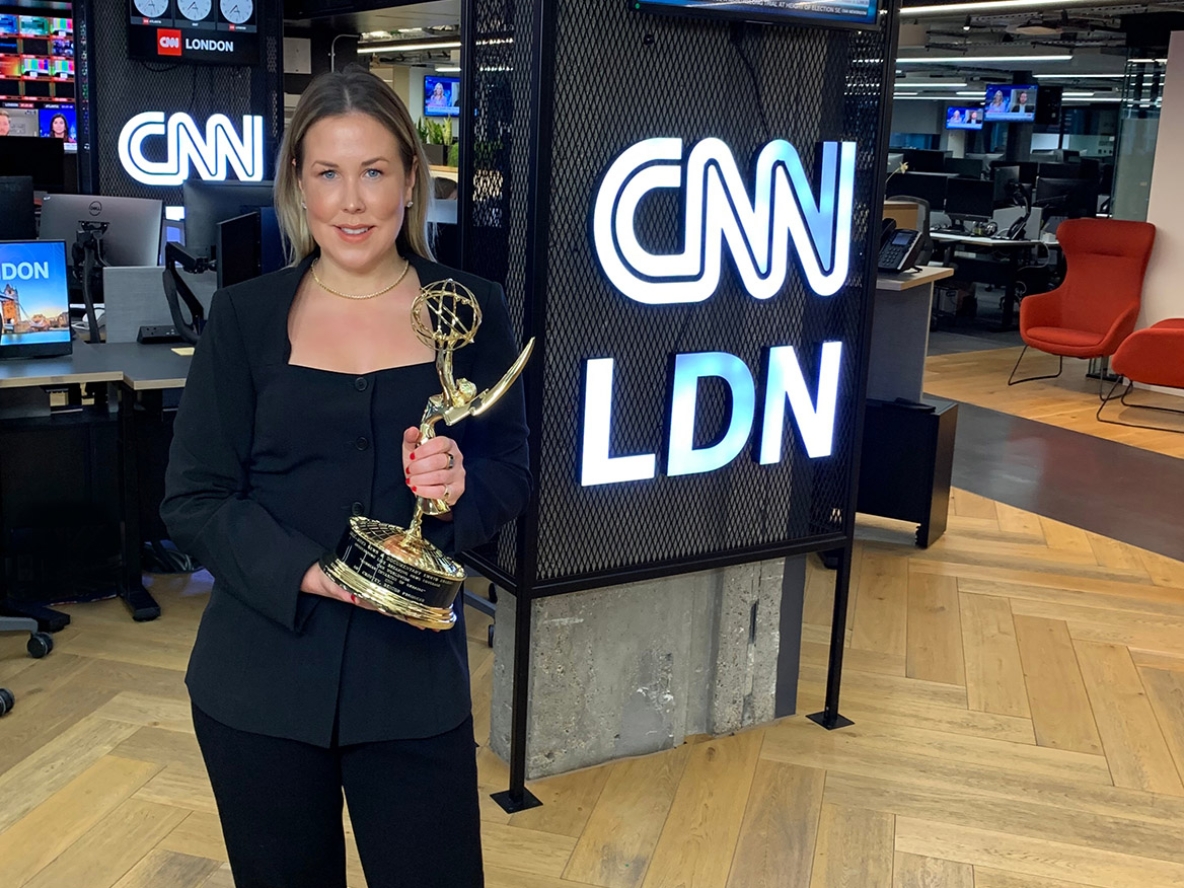 A woman with blonde hair in a black suit holding an Emmy Award in CNN's London office