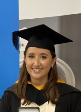 Dark haired woman wearing a graduation cap and gown
