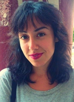 A woman with dark hair wearing red lipstick and green top