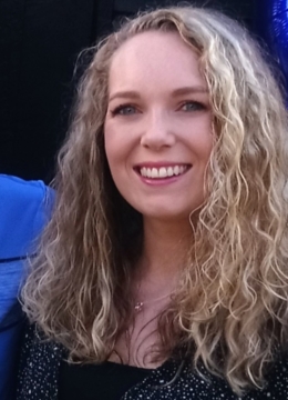 A blonde woman with curly hair smiling for the camera
