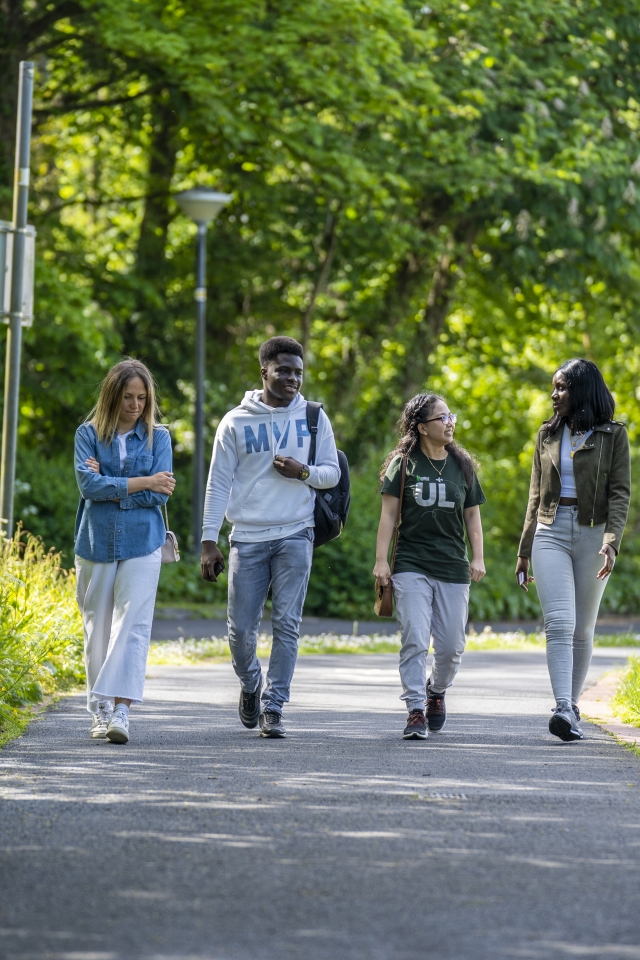 four students walking through wooded area