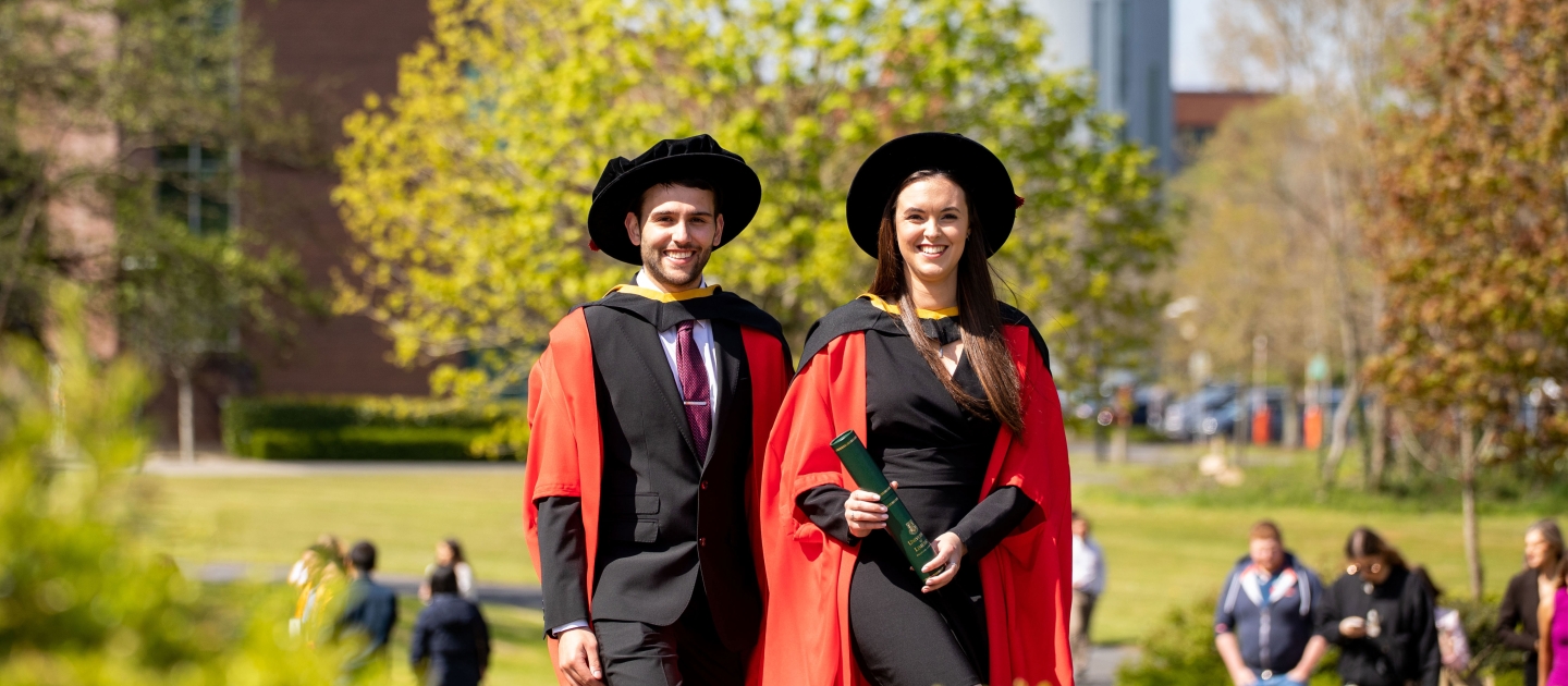 two doctoral students in graduation robes