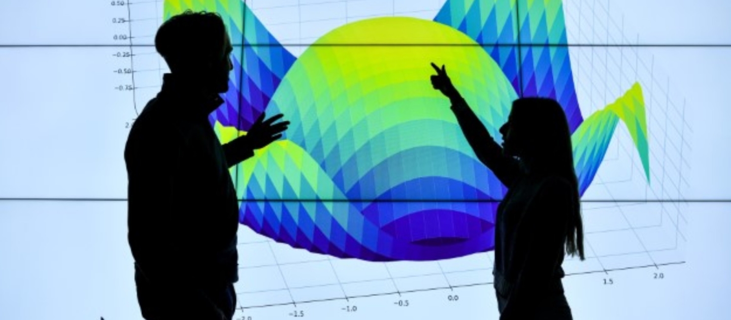 Two people standing in front of data visualisation