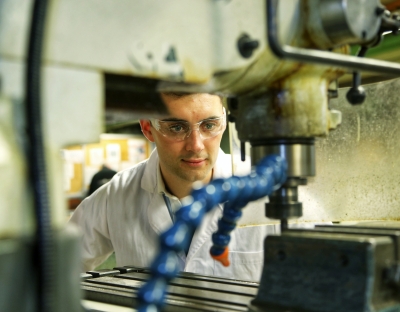 A young man looks into a drill in an engineering laboratory