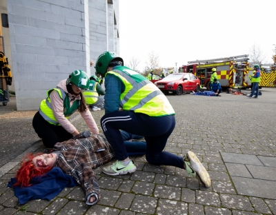 An actor victim lies on the ground while two UL student paramedics tend to her.