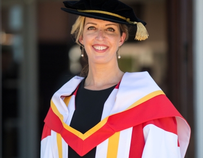 A photo of Vicky Phelan in Honorary Doctorate PhD cap and gown outside UL's Plassey House