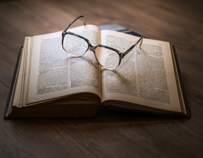 Image shows book on a table with some glasses 