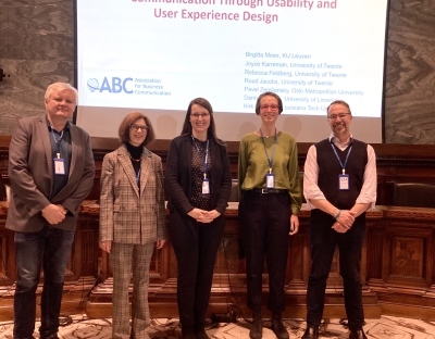 Panel presenters Pavel Zemliansky, Birgitta Meex, Darina Slattery, Joyce Karreman, and Kirk St.Amant smiling for a photo in front of a PowerPoint slide.