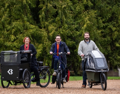 Professor Kerstin Mey, sitting on a tricycle style e-bike, Dr James Green also on a e-bike and Brian Leddin TD on an e-bike with a childrens carrier in the front. 