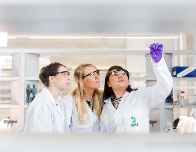 three women in lab coats examining test tube