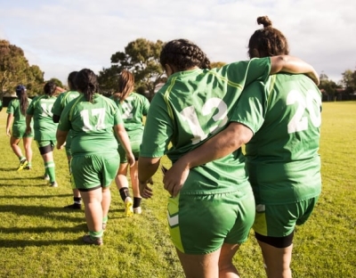 Female Rugby players walking arm in arm on a field