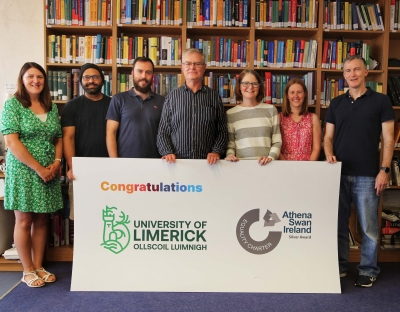 Members of the Department of Mathematics and Statistics at UL pictured with large sign marking their Athena Swan award