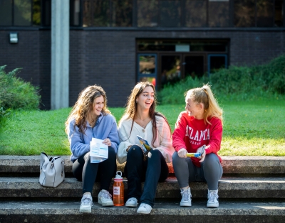 three chatting female students sitting on steps outside