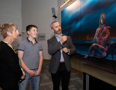 Three people looking at a large painting - they are Vicky Phelan's mother and son and friend David Brennan
