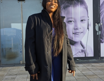 A photo of Annabel standing outside wearing a black coat and blue pants.