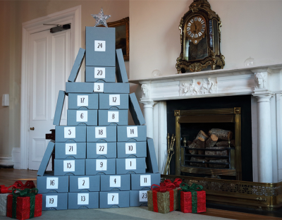 collection of boxes in Christmas tree shape in front of a fireplace