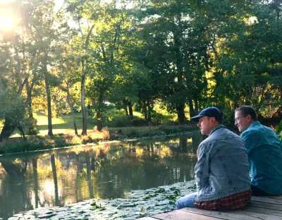 Two men staring at water with trees in background