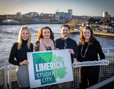 Alli McNamara and Global staff from other Limerick colleges holding Limerick Student City signs in front of the River Shannon