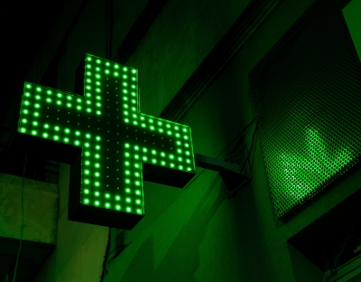 Pharmacy cross lights up with green LEDs over a door