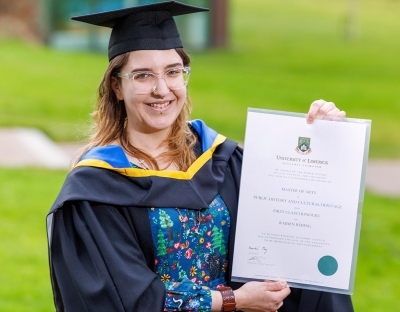 University of Limerick graduate Kaiden Reding holding her diploma in a cap and gown