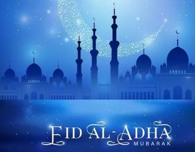 Image exclaims Eid Al-Adha Mubarak with buildings and sky in the background in blue and gold