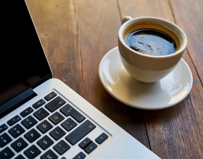 Image shows a cup of coffee and a laptop 