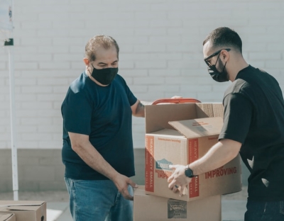 Man passing another man a box of food waste.