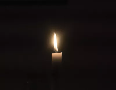Image shows a single candle against a dark background