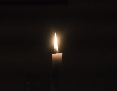 Image shows a single candle against a dark background