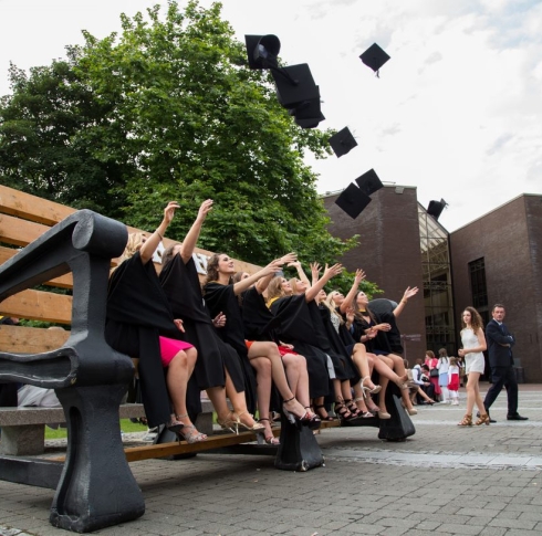 Graduates on a giant seat, throwing hats