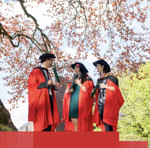 3 PhD graduates in their red robes