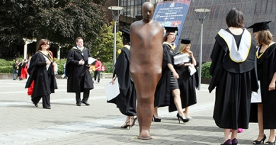 students on graduation day beside brown thomas statue