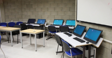 Several computers set up at desks against a grey block wall