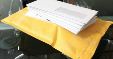 A stack of brown and white envelopes on a glass table