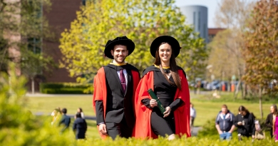 two doctoral students in graduation robes