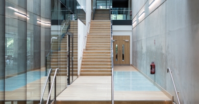 A large staircase in a building with glass windows to the left of the stairwell