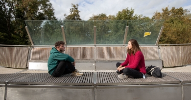 two students sitting on a bench and talking