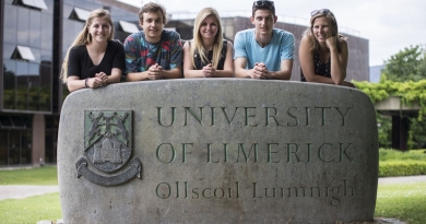 5 students standing behind rock that has University of Limerick and the heraldic crest on it