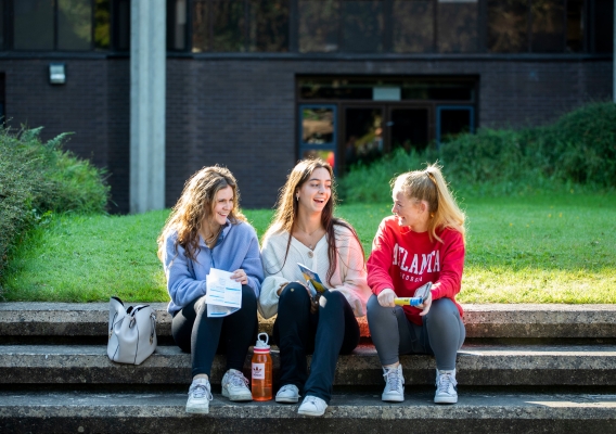 three chatting female students sitting on steps outside