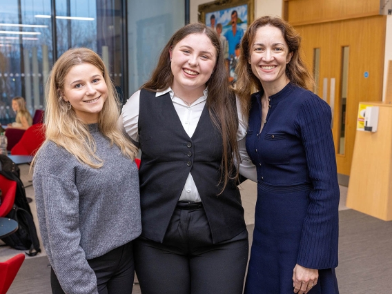 Three women in a corporate building standing smiling for the camera