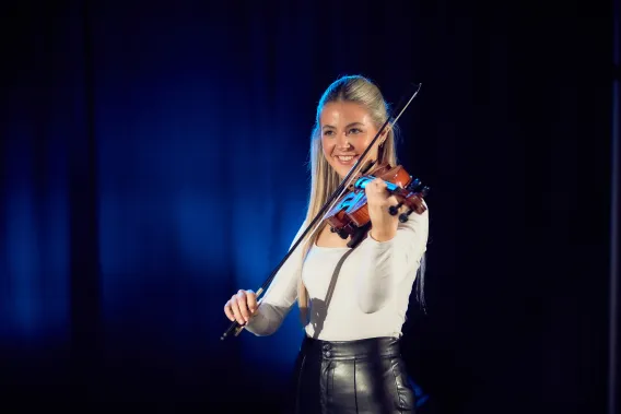 Fiddle player on stage smiling at the audience