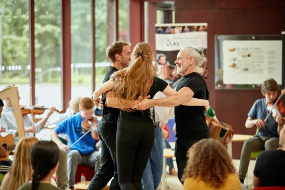 Three dancers with their arms around each other dancing to Irish music