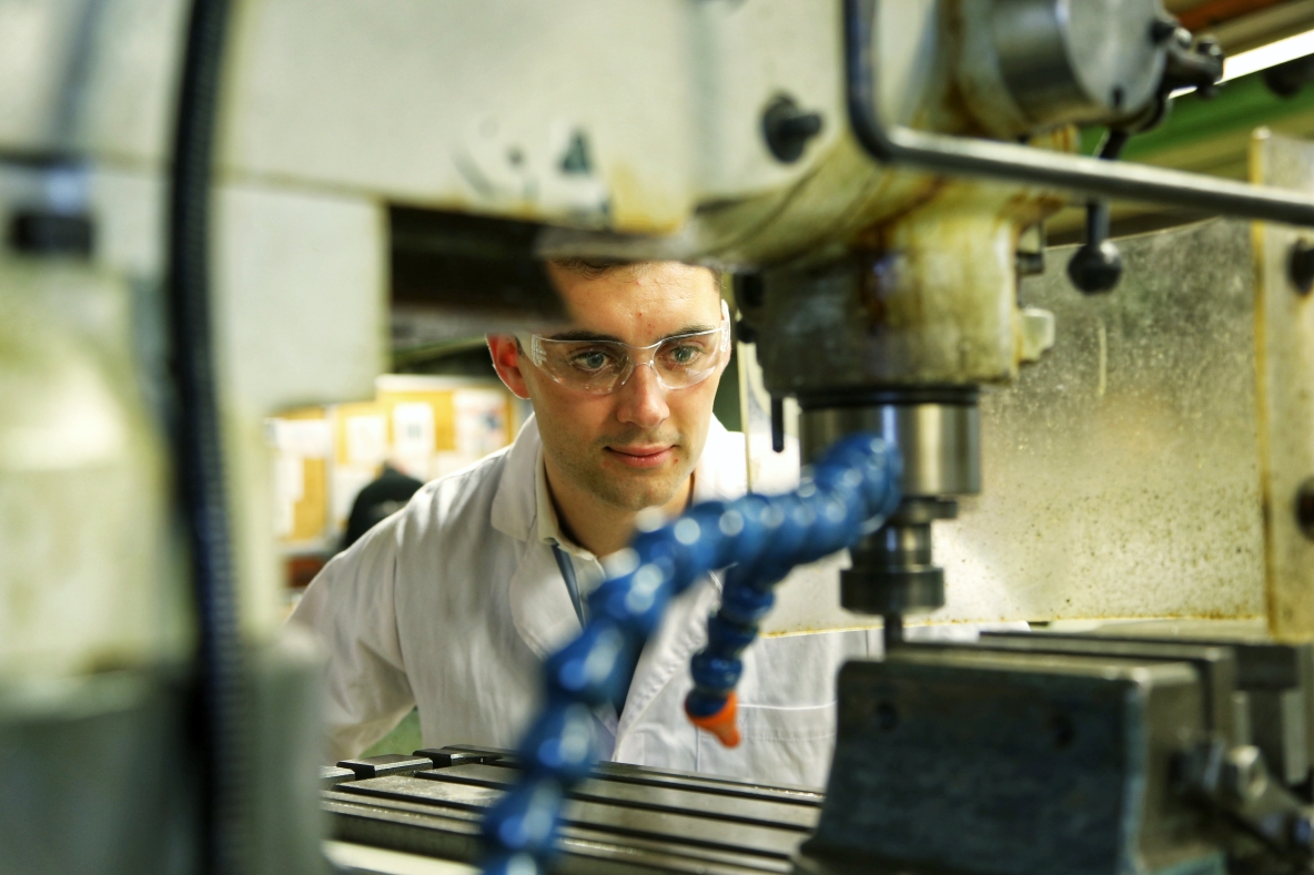 A young man looks into a drill in an engineering laboratory