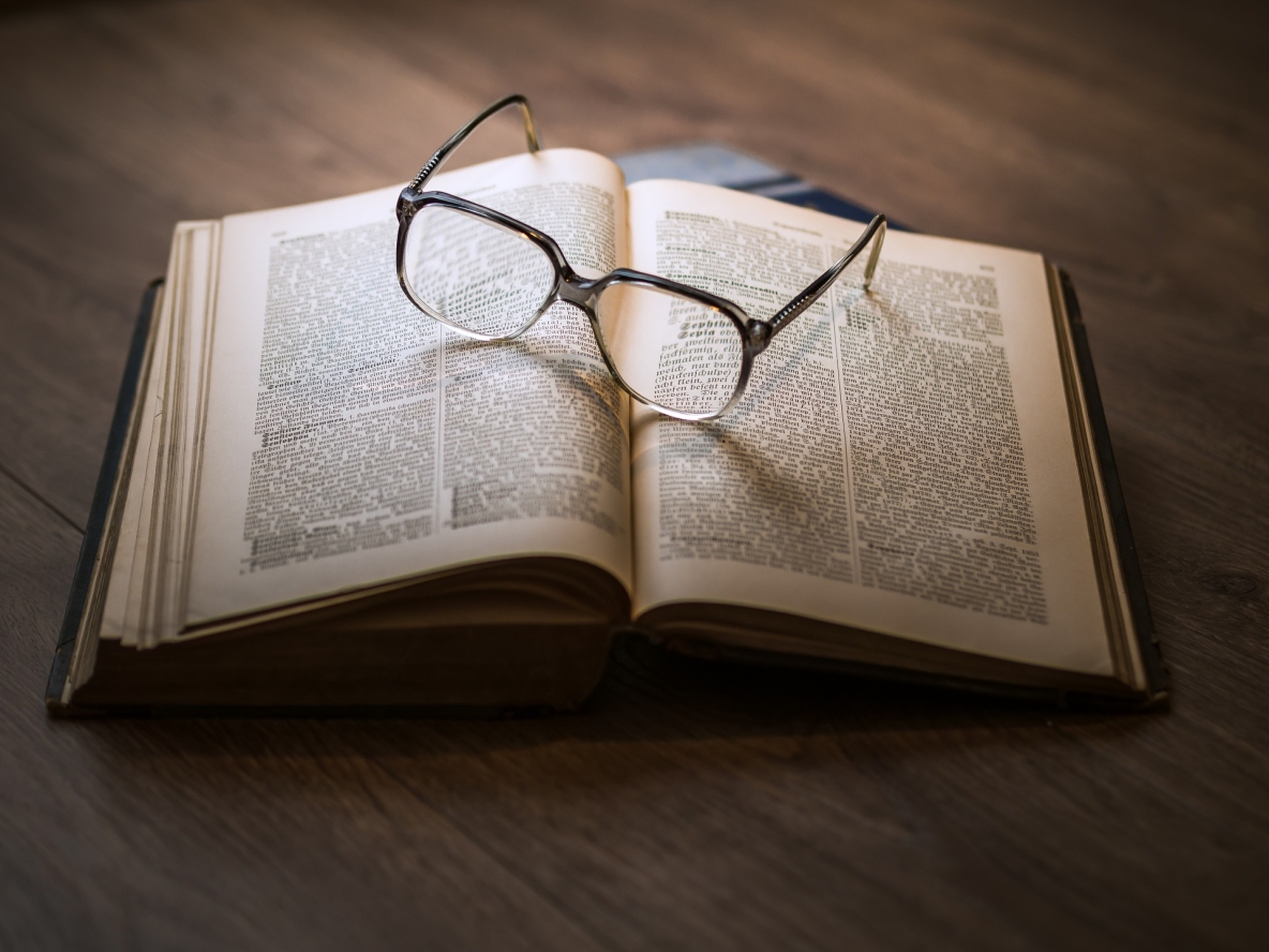 Image shows book on a table with some glasses 