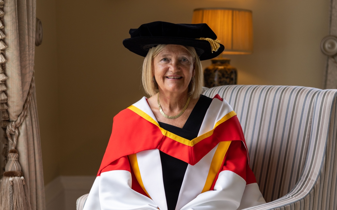 A picture of Professor Brigid Laffan in her robes, sitting in a chair