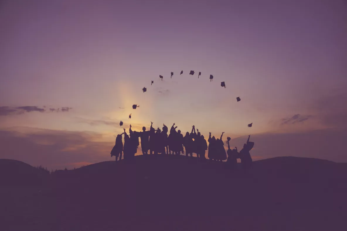 Image of graduates throwing their caps in the air